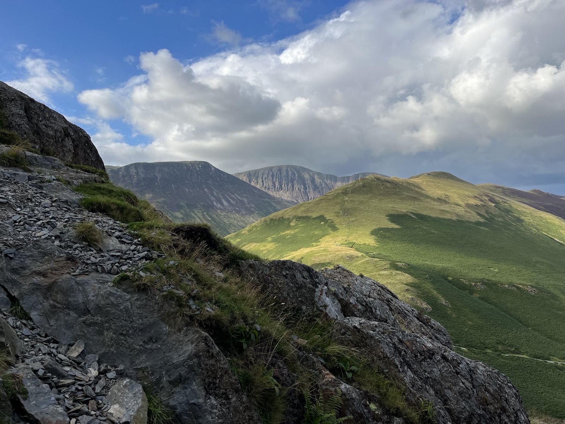 Mountain landscape with green hills and dramatic clouds, reflecting personal growth and new perspectives promoted by June Reid Counselling.