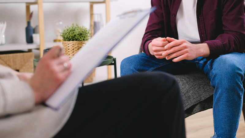Counsellor taking notes while listening to a client during a therapy session