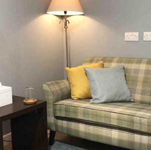 Interior of June Reid Counselling room with comfortable sofa, cushions, and soft lighting.